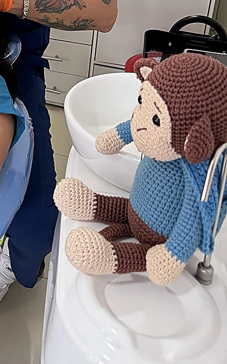 Mono de peluche tejido sentado junto al sillón dental